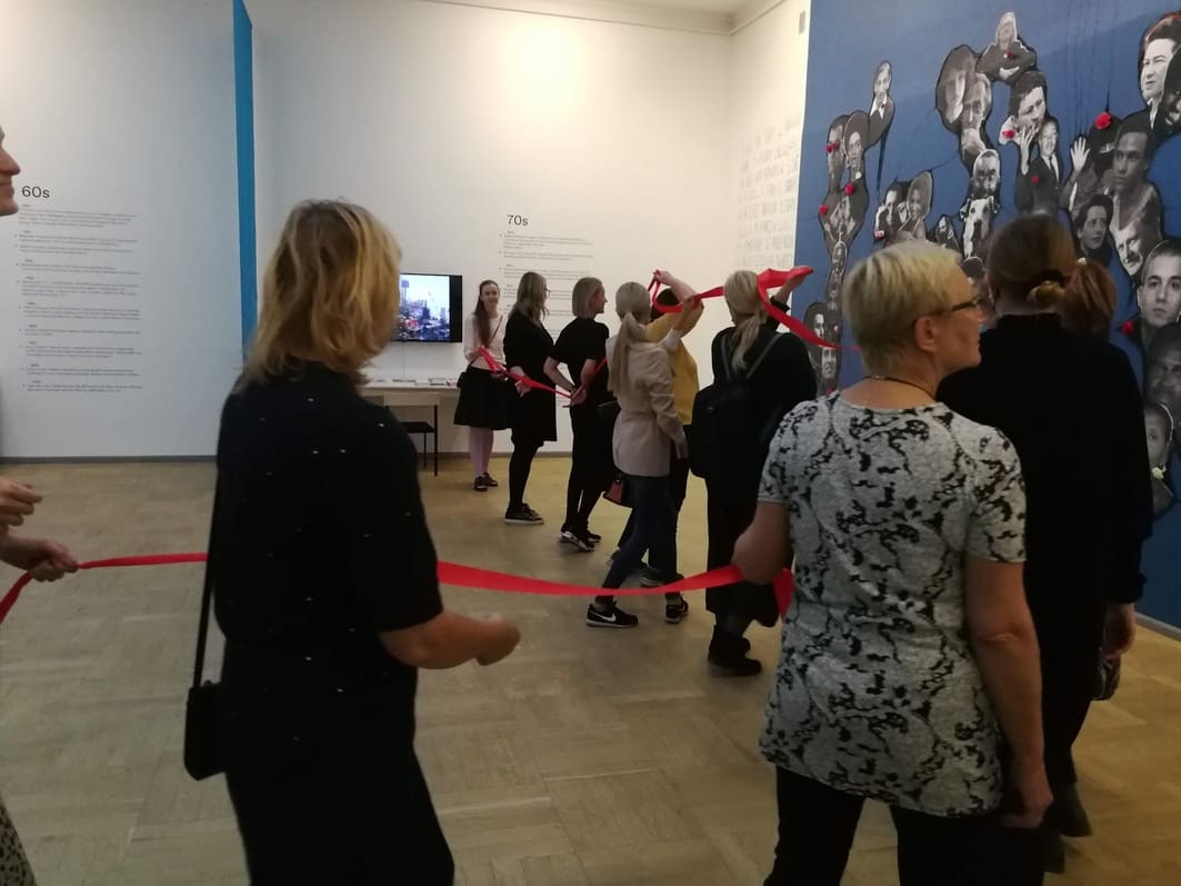 Õpetajad ühendatuna punase lindiga Kunstihoone näitusel