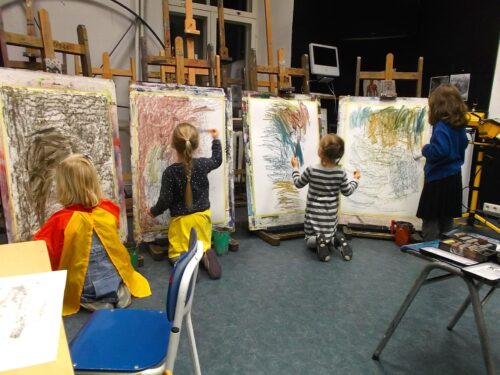 Fotol on kujutatud nelja last molbertite ees suurtele paberitele ekspressiivselt joonistamas
