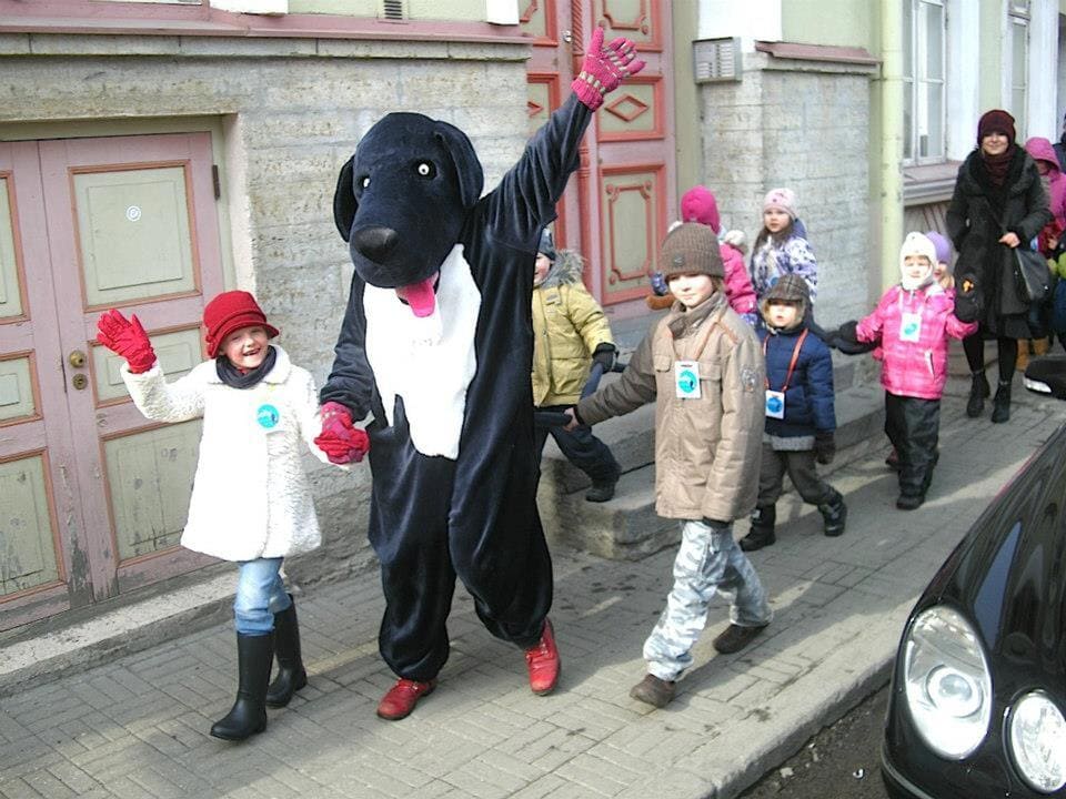 Maskotiga koos läbi linna liikuvad lapsed