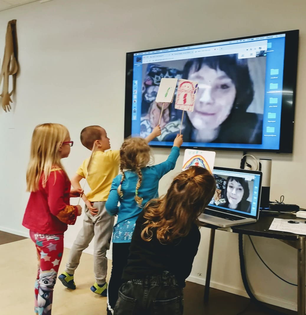 Fotol on kujutatud õpilasi, kes näitavad oma töid õpetajale, kes on tunnis virtuaalselt ega ekraani vahendusel