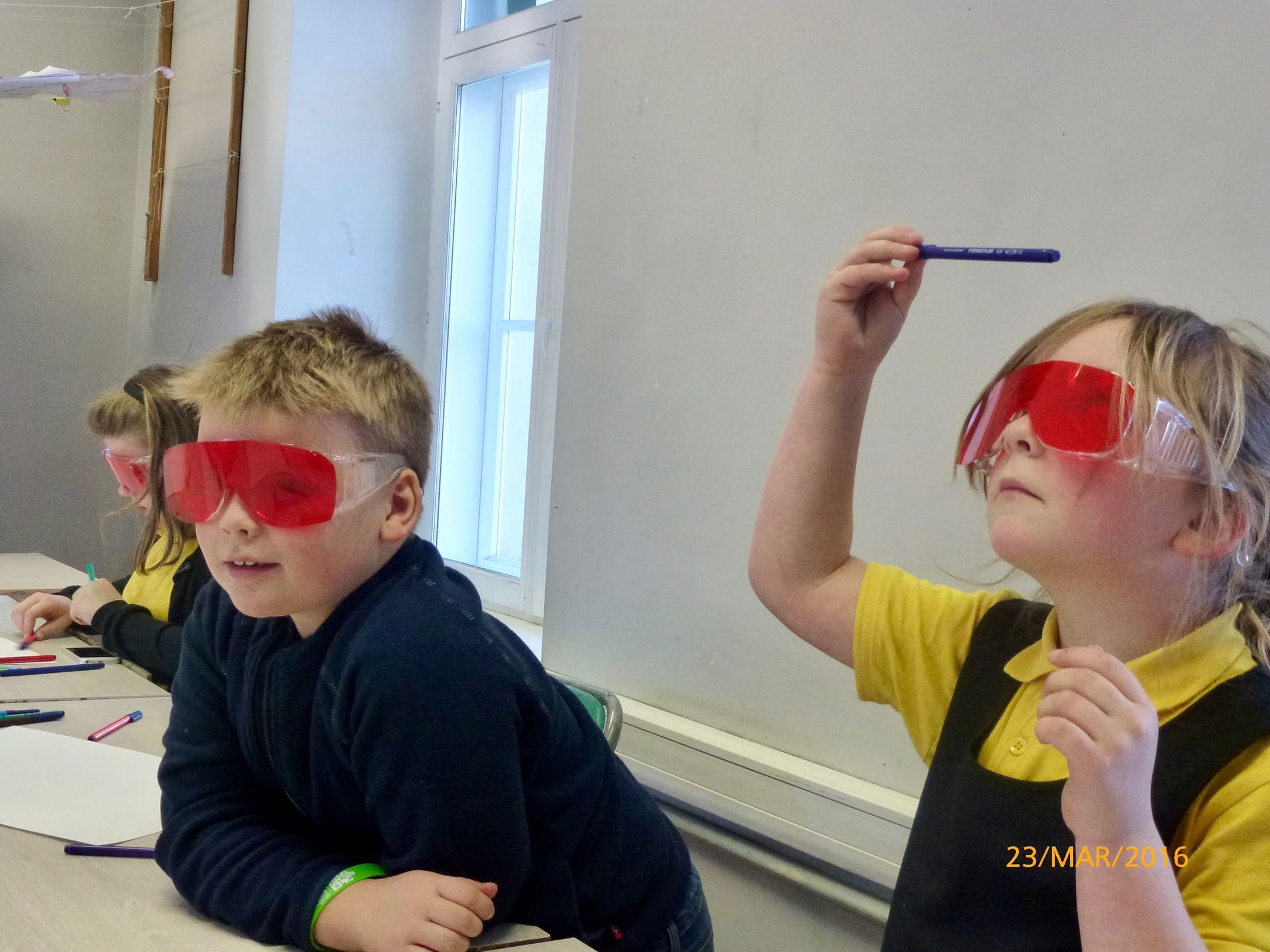 Foto kujutab punaste prilliklaasidega õpilasi uurimas pliiatsit ja end ümbritsevat keskkonda