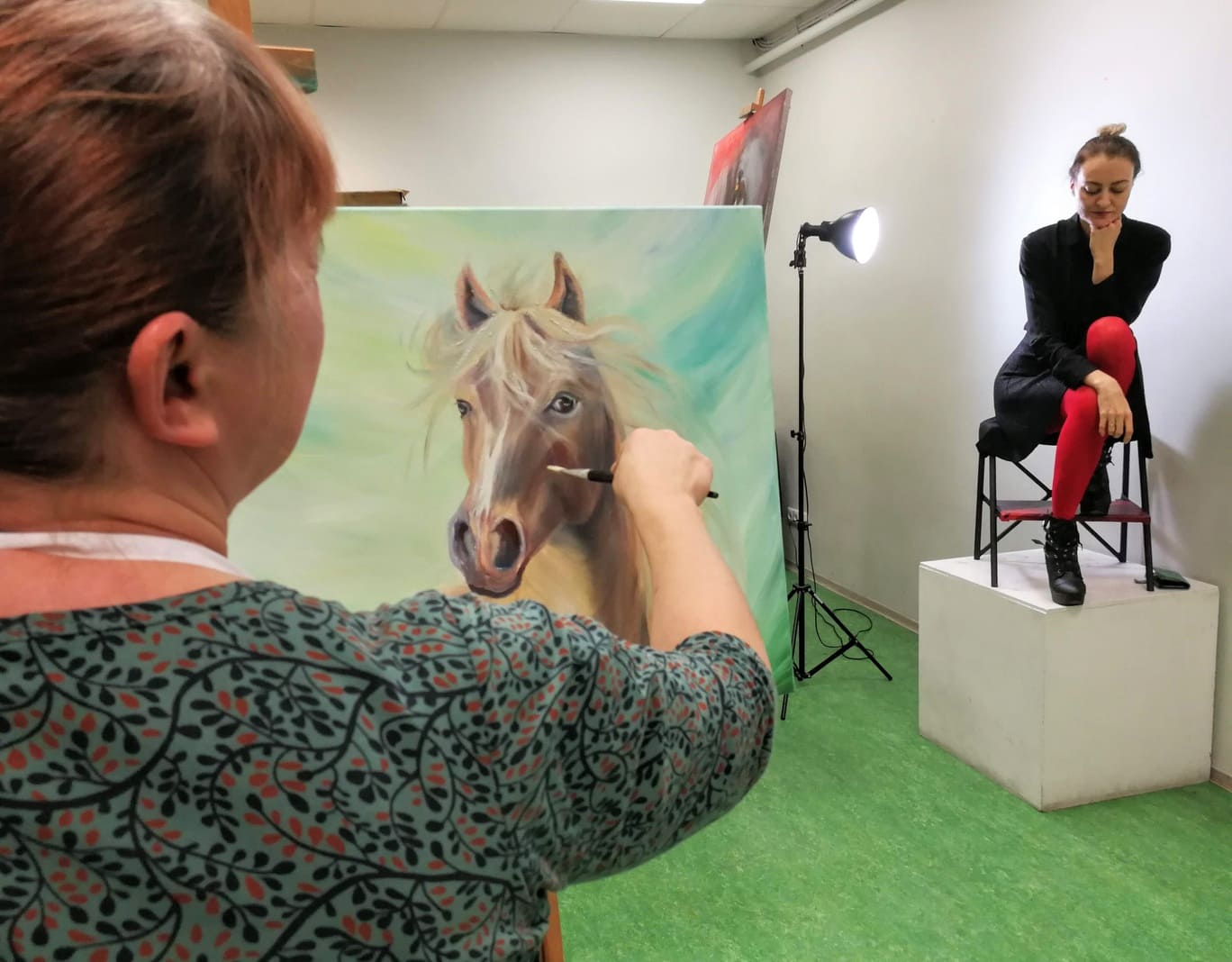 Maalija maalib hobust vaadates naismodelli