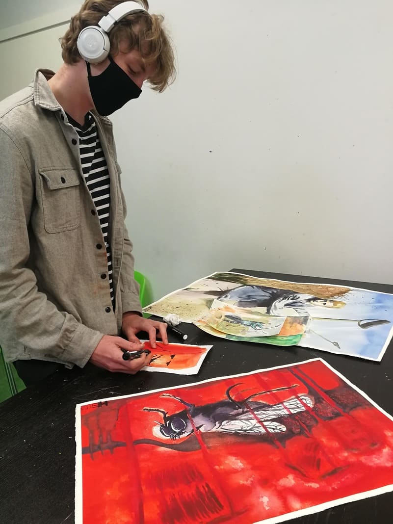 Fotol on kujutatud kõrvaklappide ja musta maskiga noormeest, kes maalib